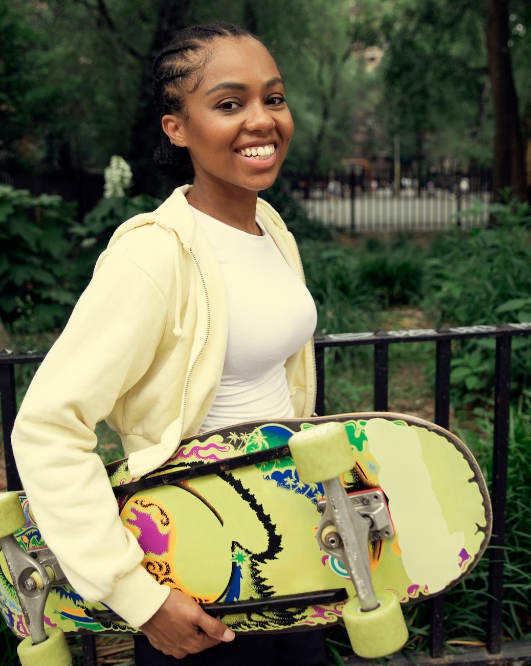 Leende kvinna som bär en skateboard i en park