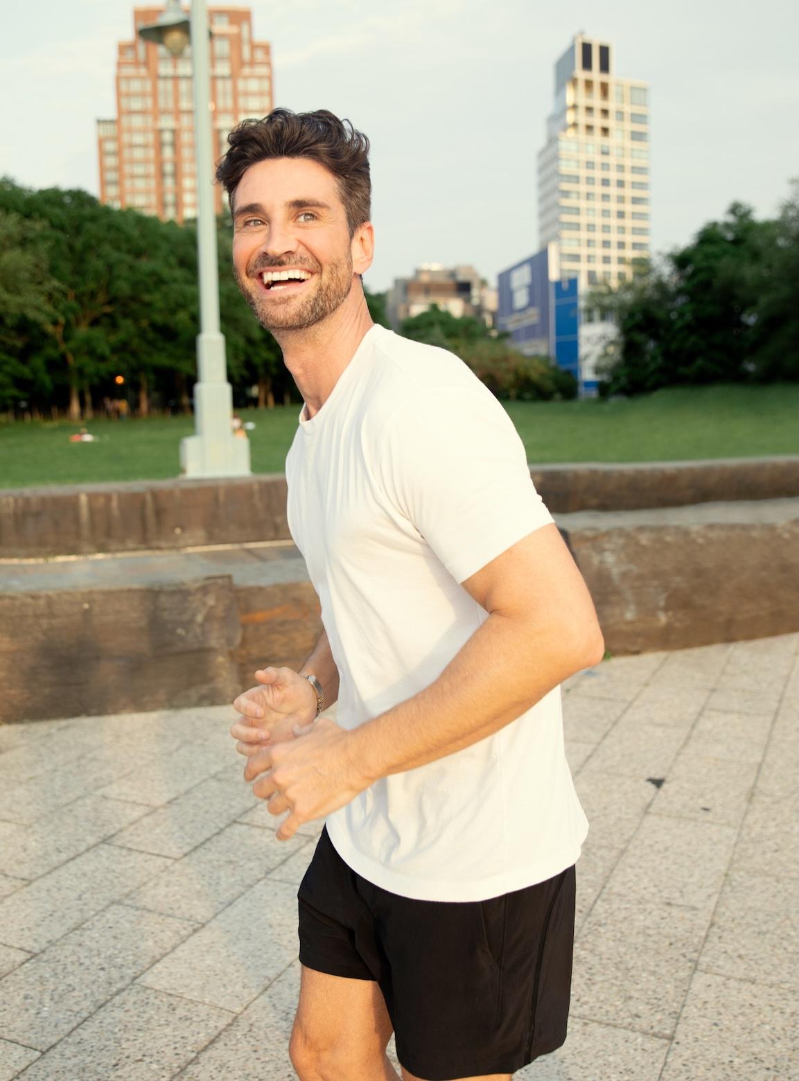 En man som joggar och ler i en stadspark